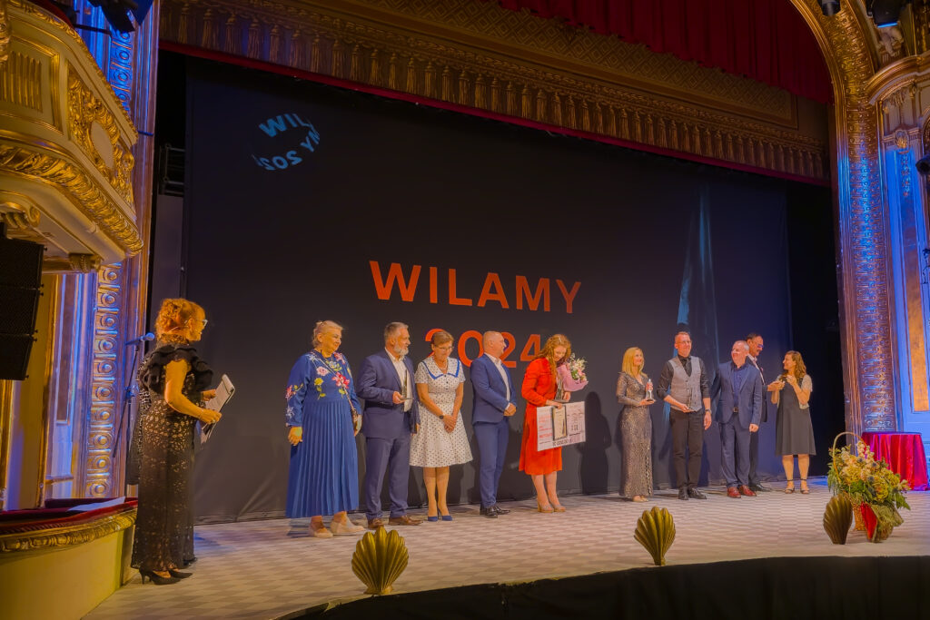 Laureaci Gali Wilamów 2025 pozują do wspólnego zdjęcia na scenie Teatru Horzycy, z napisem "WILAMY 2024" w tle.